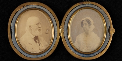 Two sepia photographs in oval frames, showing an elderly couple facing each other