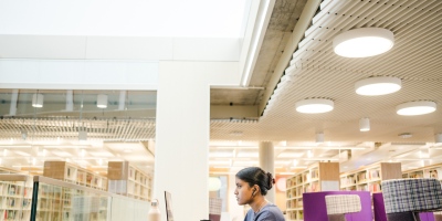 A student working on a laptop in the Edward Boyle Library